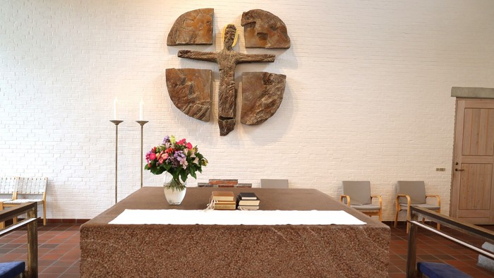 En kirkeindretning med alter, blomster og krucifiks