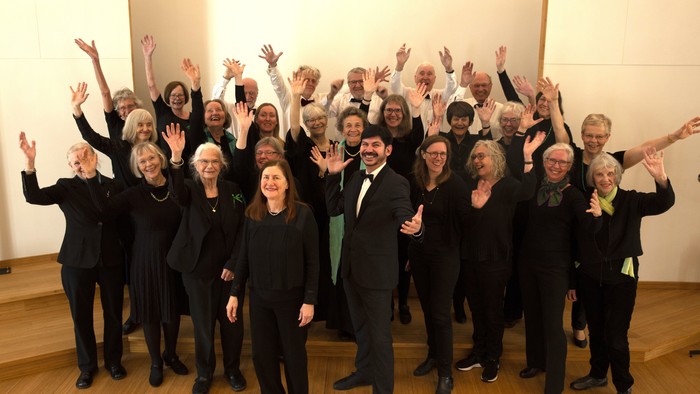 En gruppe af mænd og kvinder i formel klædning står sammen med arme i luften.