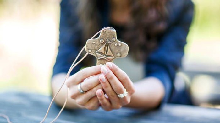 Eine Frau hält eine goldene Herzform in den Händen.