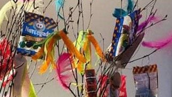 En vase med grene og farverige papirfjer.