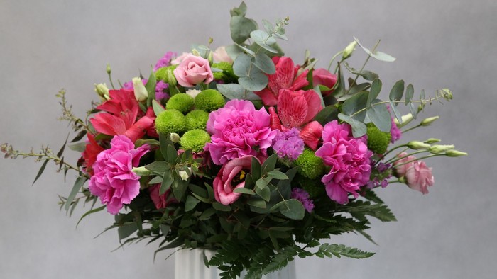 Ein Blumenstrauß mit rosa und grünen Blumen in einer Vase