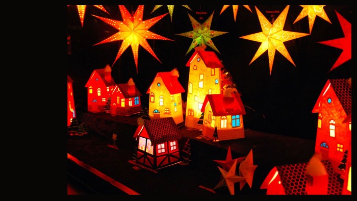 Leuchtende Papierhäuser und Sterne im dunklen Raum