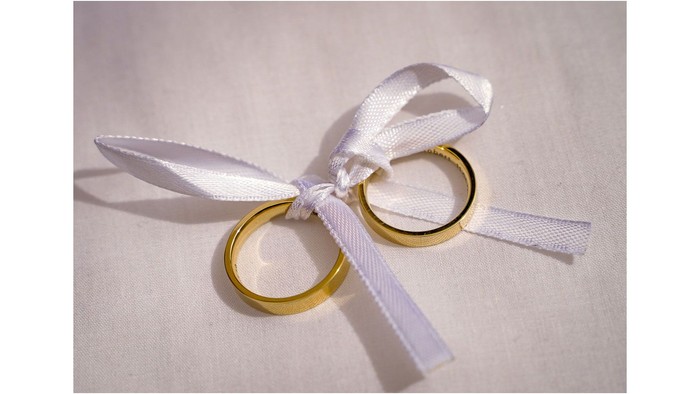 Zwei goldene Ringe mit weißer Schleife