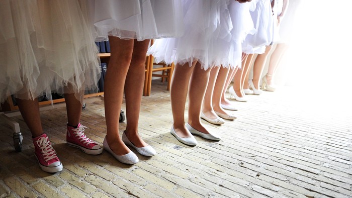 En rekke danser i balettstøvler og strømper, en med rosa sneakers.