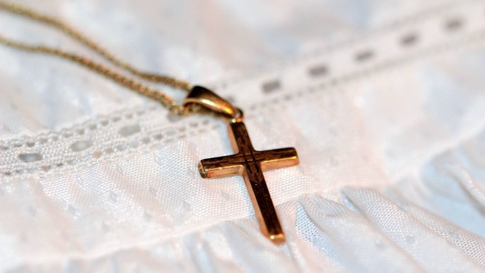 En guldkæde med kors med blødt stof i baggrunden