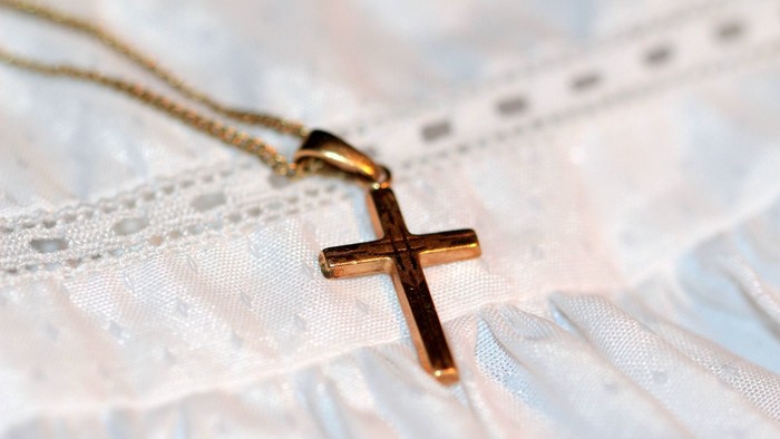 En guldkæde med kors med blødt stof i baggrunden