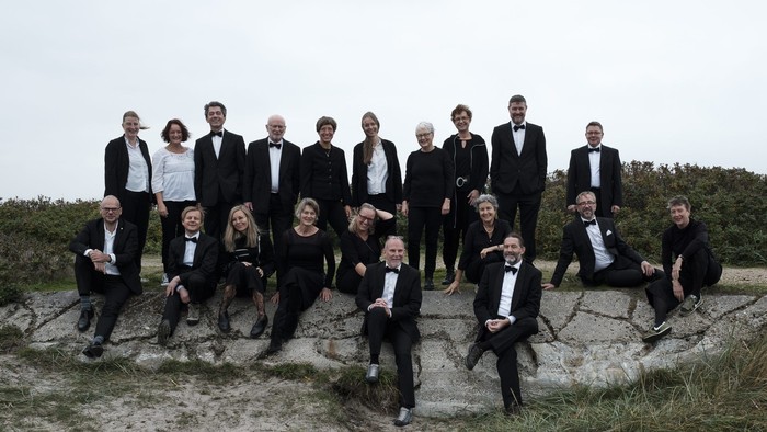 En gruppe formelt klædte mænd og kvinder poserer på klipper ved stranden