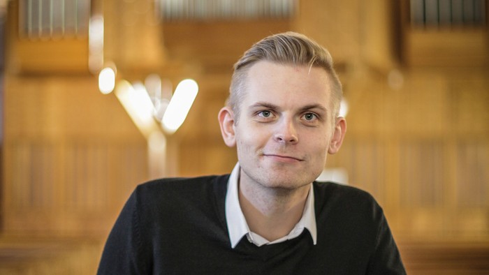 Mand i sort trøje står i kirke.