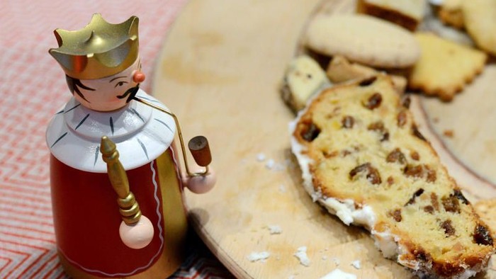 Eine Holzfigur mit Krone steht neben einem Teller mit Kuchenstücken.