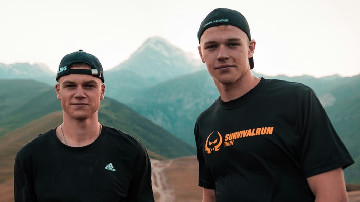 Zwei Männer in Berglandschaft mit Survivalrun-T-Shirts