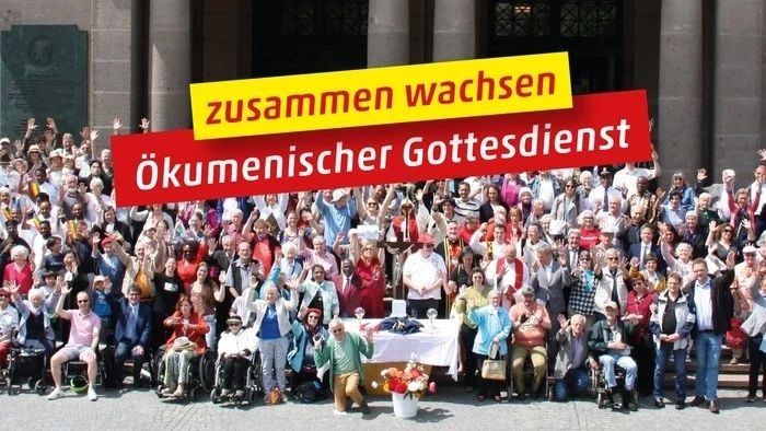 Große Menschenmenge vor Gebäude mit Protestschild "zusammen wachsen ökumenischer Gottesdienst"