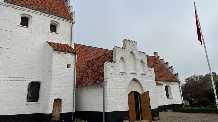 Hvidt kirke med røde tag og flagstang.