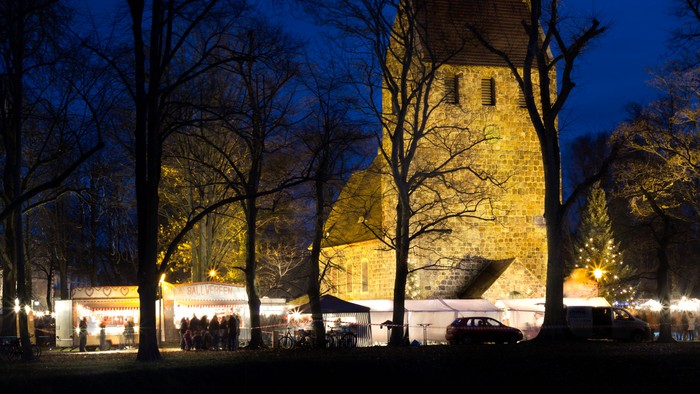 Bewohnter Turm bei Nacht mit beleuchteten Bäumen und Autos