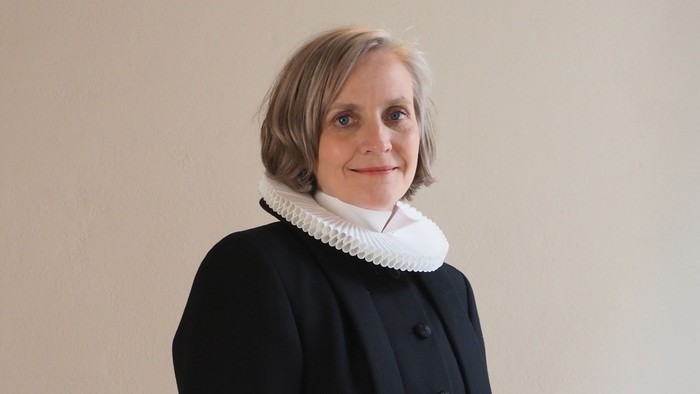 Kvinde i sort kaptajnmø, hvid krage og hvid kuffe.