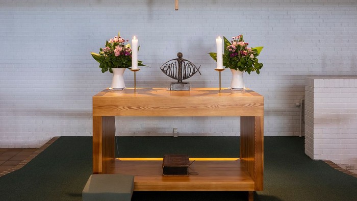 En moderne kirkeinteriør med alter, lys og blomster.