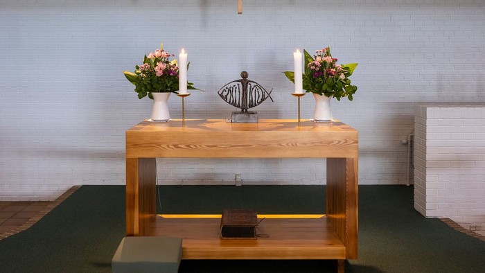En moderne kirkeinteriør med alter, lys og blomster.