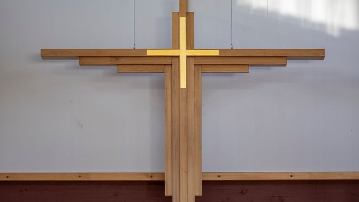 En stor, gul korsformet pryd på en hvide mur med et vindue ovenfor