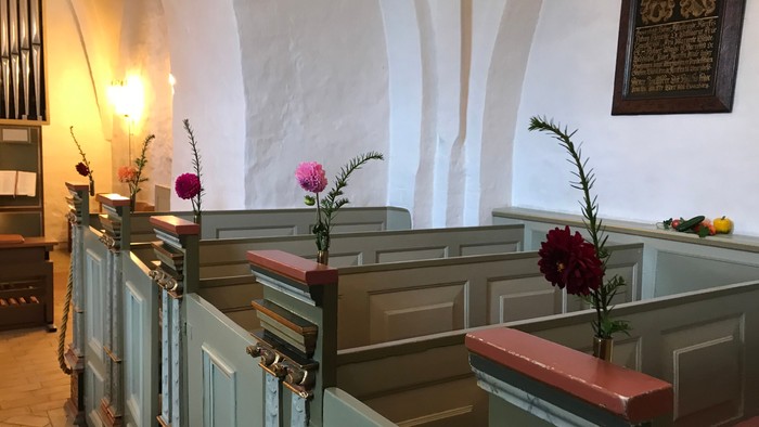 Bænke med blomster i kirke.