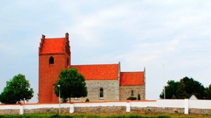 En rød kirke med tårn og et hvidt telt foran, omgivet af en grøn og guld farvet marker.