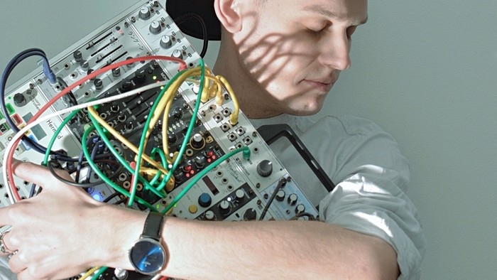 Mand med hat holder en elektronisk apparat.