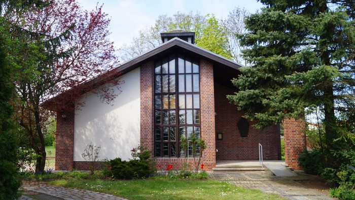 Ein modernes Ziegelgebäude mit großen Fenstern und umgeben von Bäumen und Büschen.