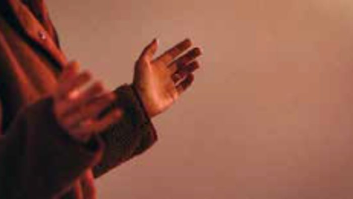 En person med håndene sammentrykt foran brystet.