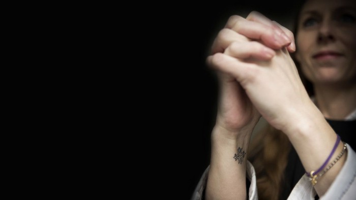 En person holder hånd med en anden person i mørke omgivelser.