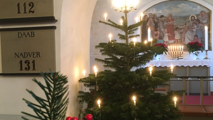 En juletree med lys og lyse kugler i en indgang, med en maleri og numre på væggen