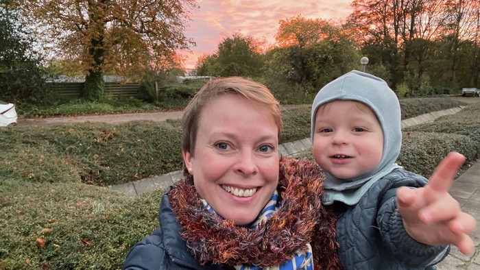 En mor og sit barn tager selfie i en park ved solnedgang