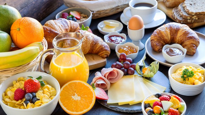 Ein reichhaltiges Frühstücksbuffet mit Obst, Croissants, Joghurt, Eiern und Getränken