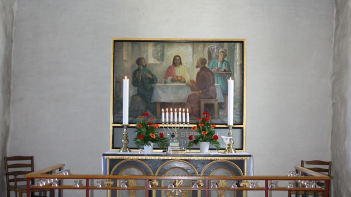 En lille kapel med billede af Jesus og apostlerne, bord og benker.