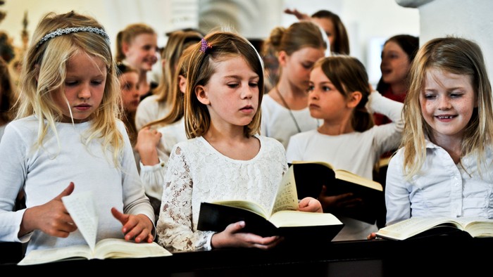Børn læser bøger i kirke.