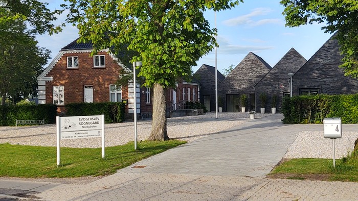 En smuk vej med træer og hus.