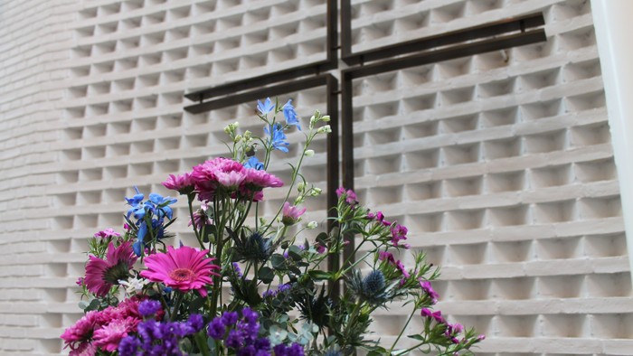 Blomsterarrangement foran mur med kors
