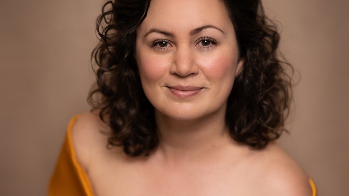 En kvinde i et gult, skulderfrit kleid.