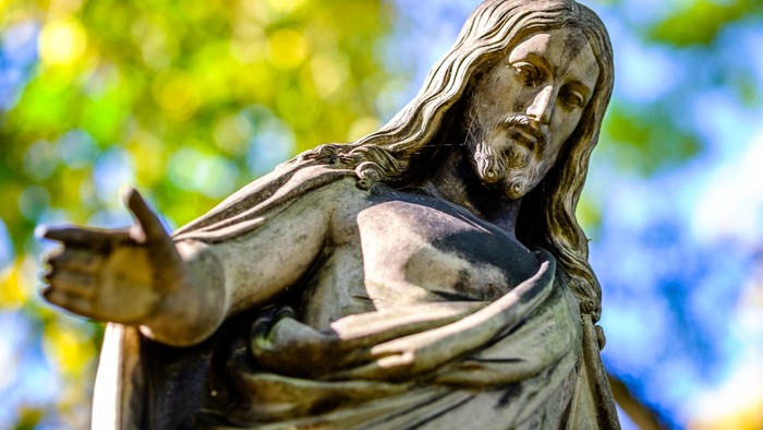 Statue af Jesus med udstrakt arm.