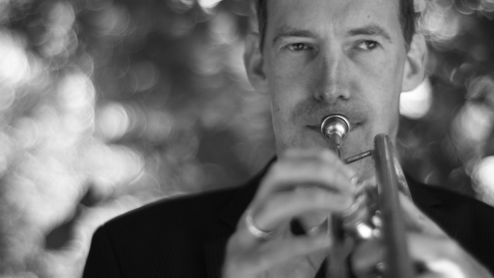 Mand spiller trompet i sort-hvid foto.