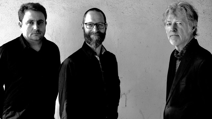 Tre mænd står sammen i sort-hvid foto.