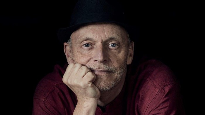 En mand sitter med hovedet på hånden ved et piano.