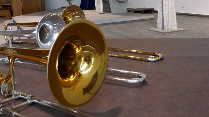 Ein goldenes und silbernes Blasinstrument liegt auf einem Holzboden in einem Raum mit Kirchenaltar.