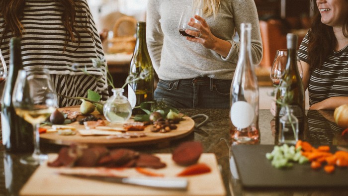 Drei Frauen genießen ein Essen mit Wein und Snacks in einem Restaurant.