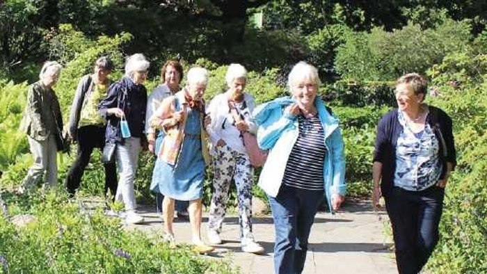 Eine Gruppe älterer Menschen spaziert in einem Garten.