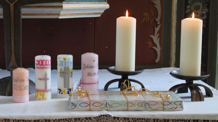 Ein Tisch mit Kerzen, Bildern und einer Vase