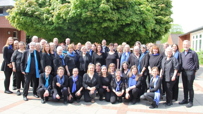 Große Gruppe von Menschen posiert vor Baum und Gebäude