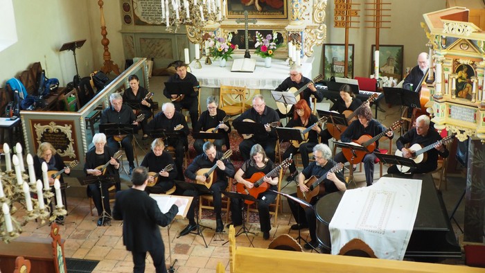 Eine Gruppe von Musikern spielt in einer Kirche verschiedene Instrumente.