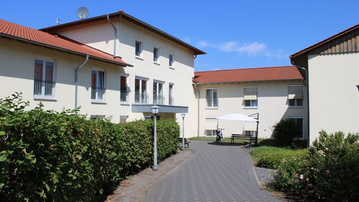 Weißes Gebäude mit rotem Dach und gepflastertem Weg