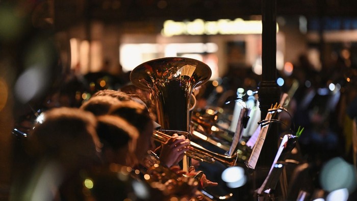 Eine Gruppe von Menschen, die in einem schwach beleuchteten Bereich Blechblasinstrumente spielt.