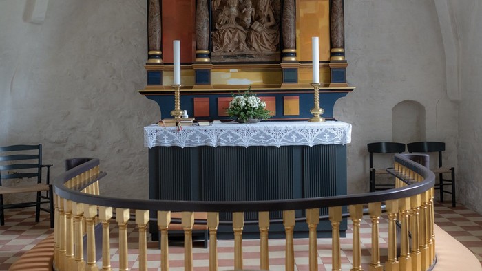 Alter i kirke med farverne blå og guld, med to lysestage på hver side.