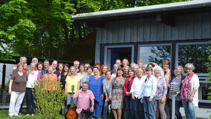 Eine Gruppe von Menschen steht vor einem Haus im Freien