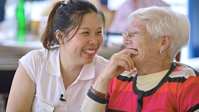 Eine junge Frau in Uniform lacht mit einer älteren Frau.